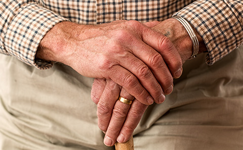Older hands crossed over a walking 